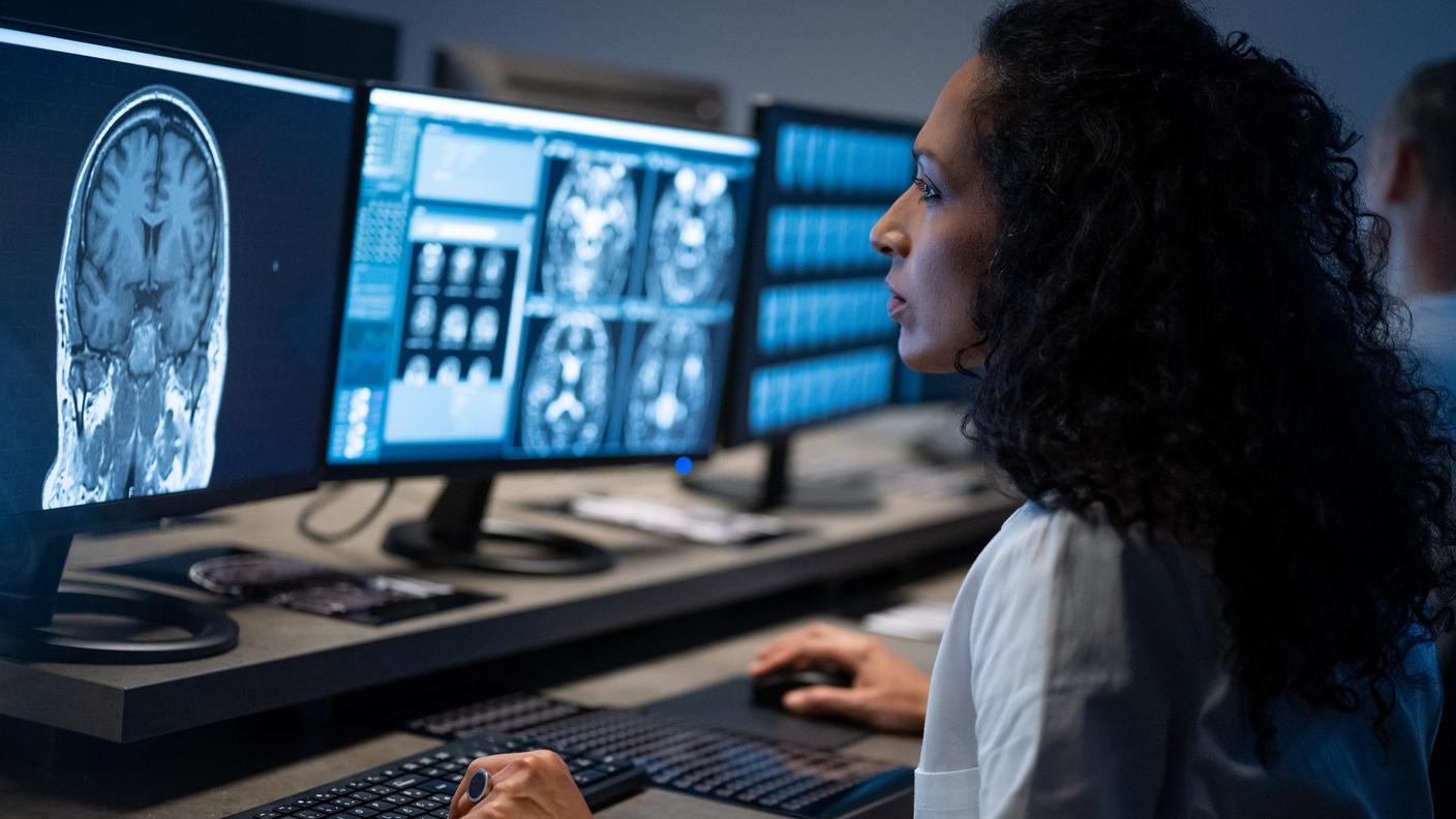 A radiation technologist analyzes brain MRI images on a computer screen