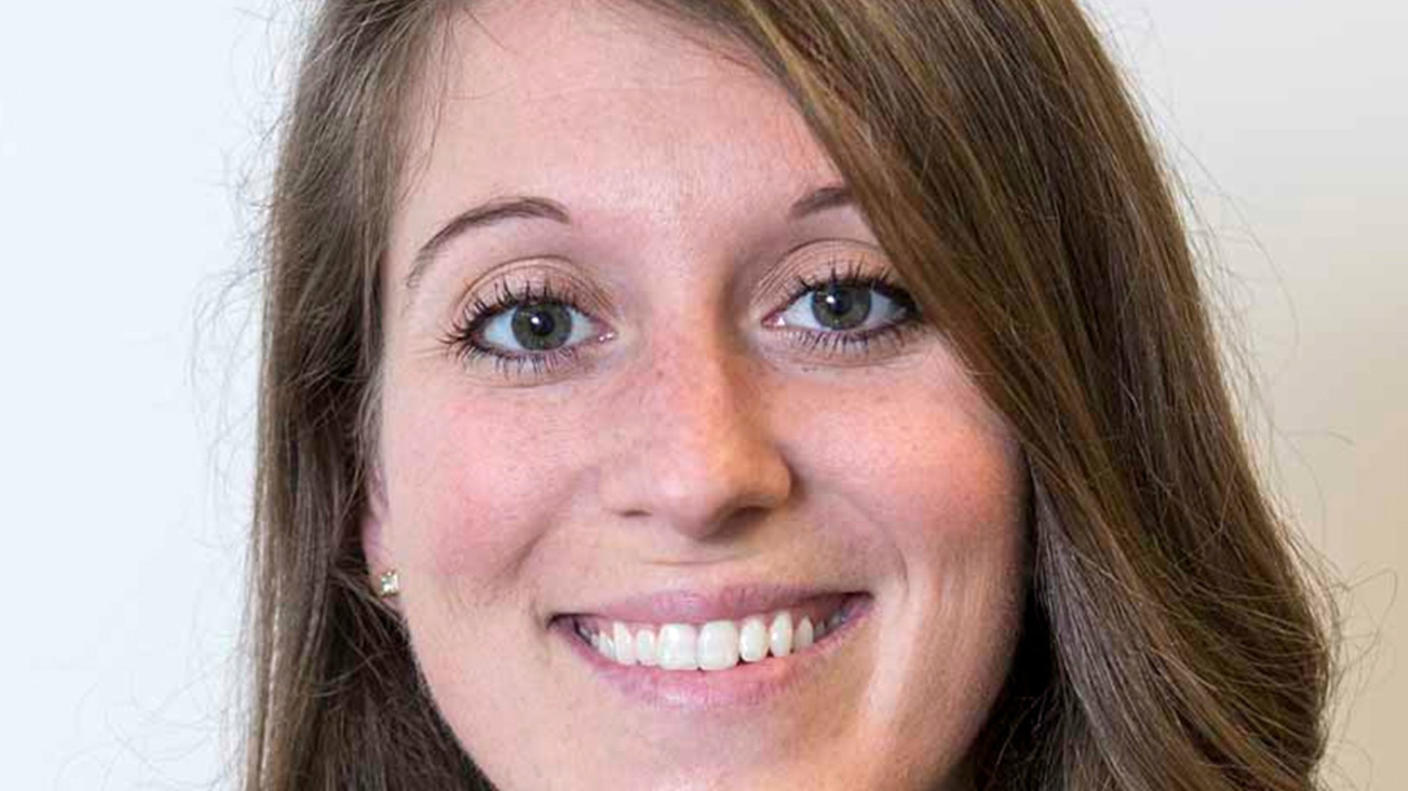 A woman, Dr. Mary Frances Wedekind, with brown hair, brown eyes, and freckles stands smiling at the camera.