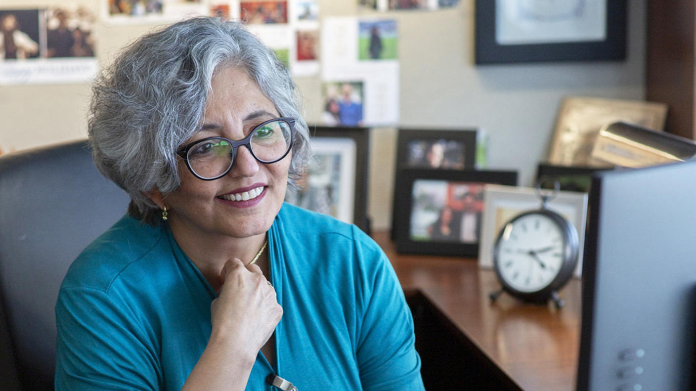 A woman, Dr. Smita Bhatia, sits in her office looking at her computer.