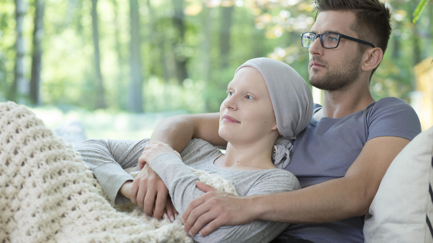 Sick woman lying in man's arms relaxing on couch.