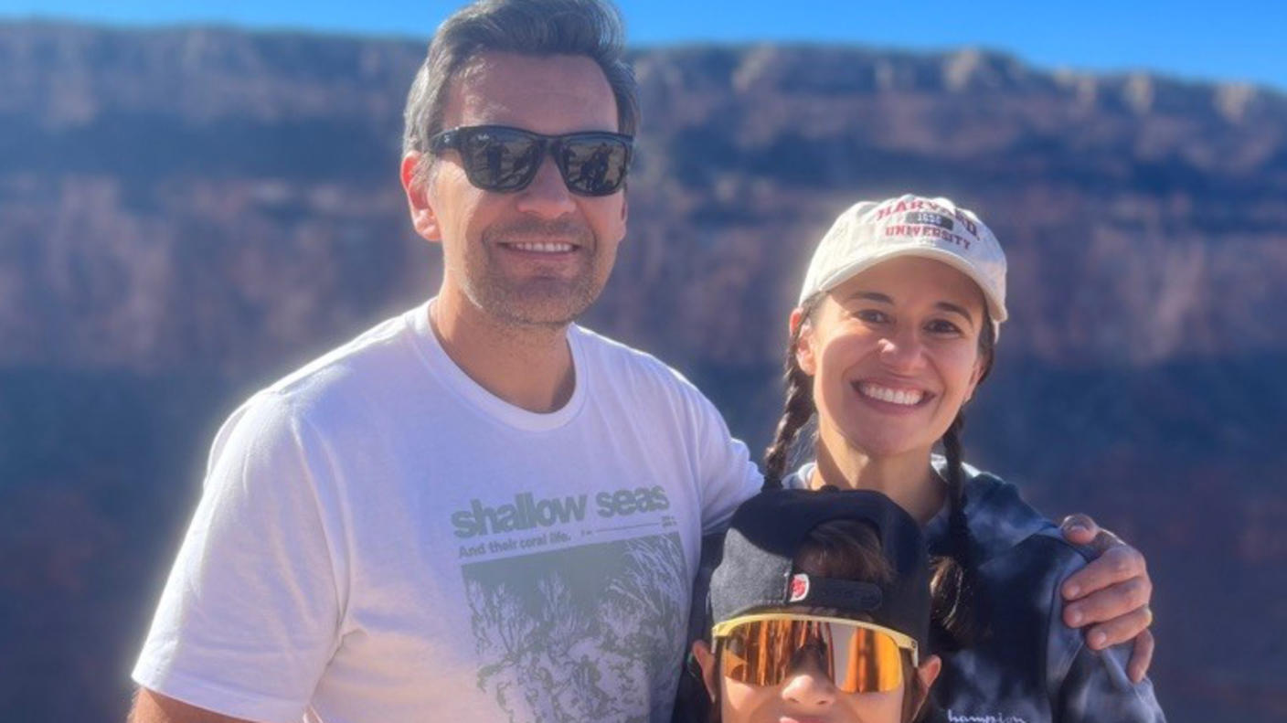 Woman, Dr. Fernanda Michels, with two long braids wearing a ballcap and sweater with her husband and young son at the Grand Canyon.
