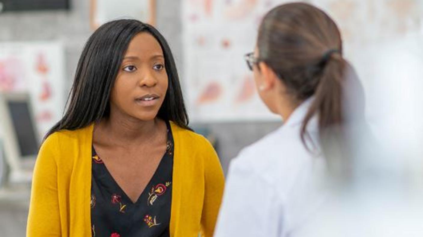 A young black woman speaking with her doctor