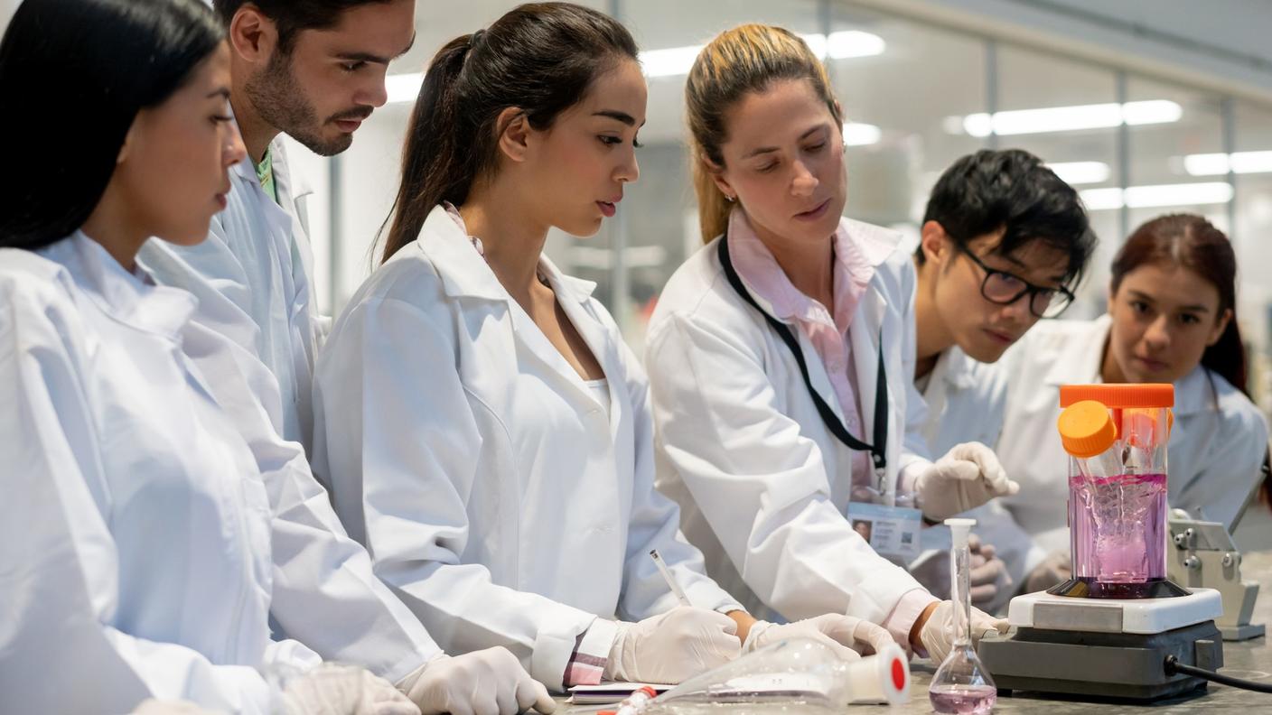 An image of a female researcher in the lab with several students to her left and right.