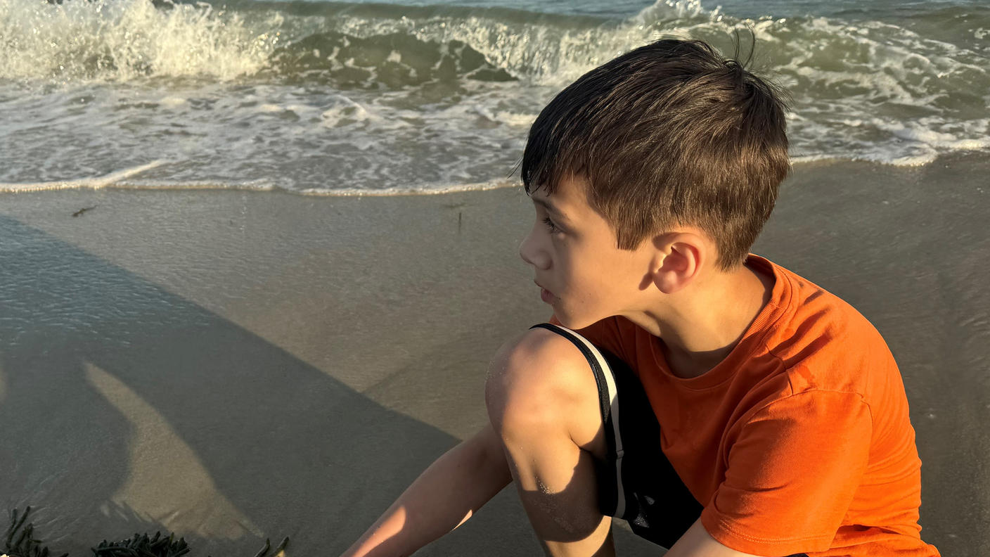 Charlie, wearing orange t-shirt and black shorts, at the beach.