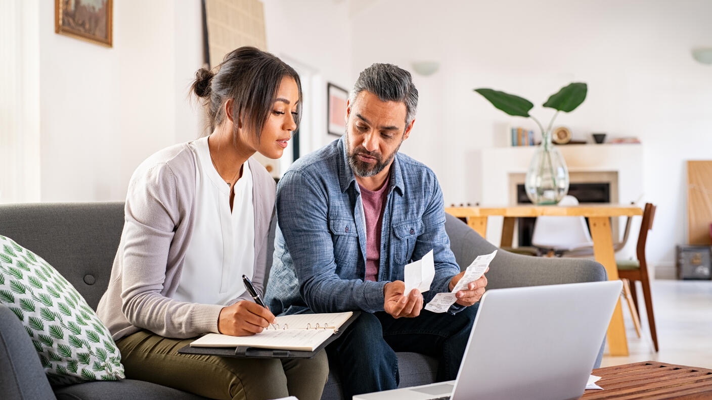 a man and woman looking at a computer and paperwork