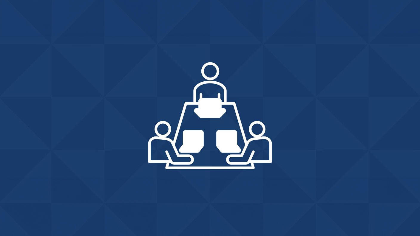 Ícono de tres personas sentadas en una mesa rectangular en la que hay computadoras.