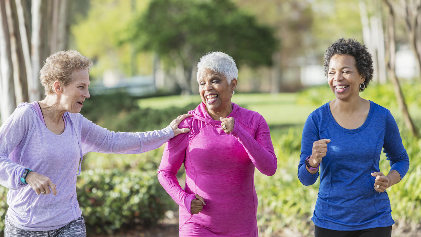 Three senior women going for a walk with one woman touching the shoulder of another woman.