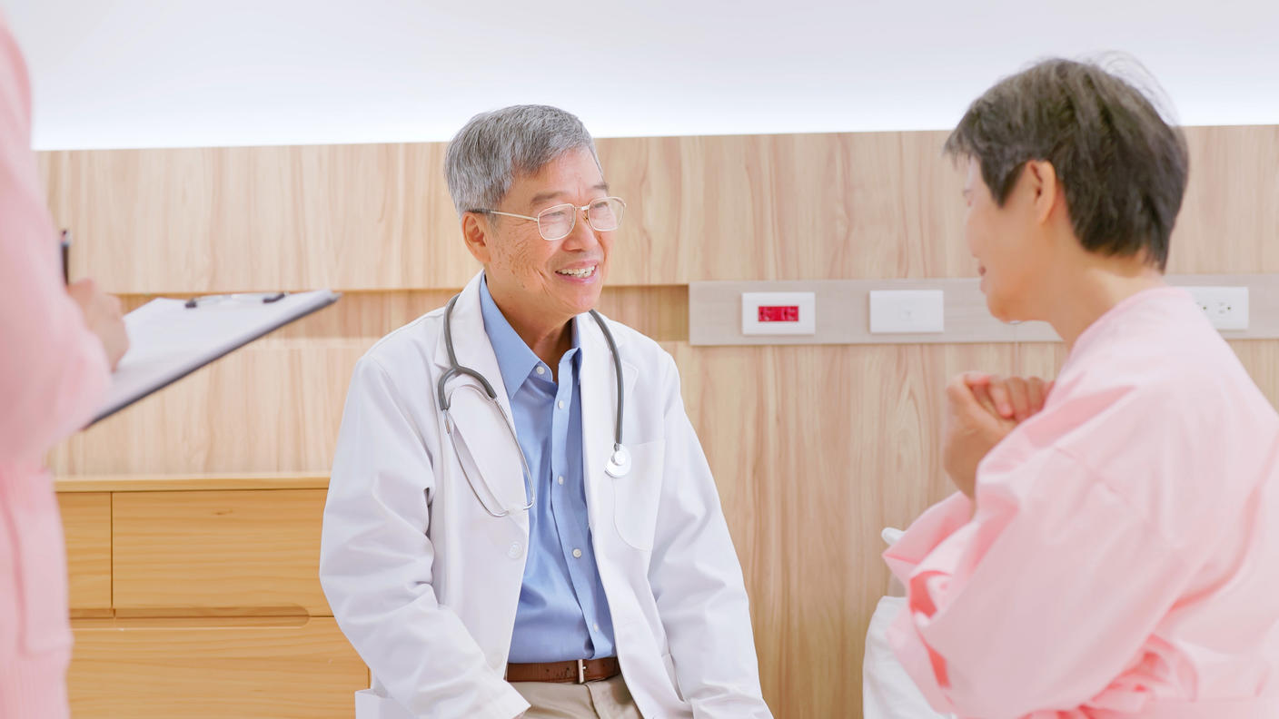 Senior male doctor talking with older female patient.