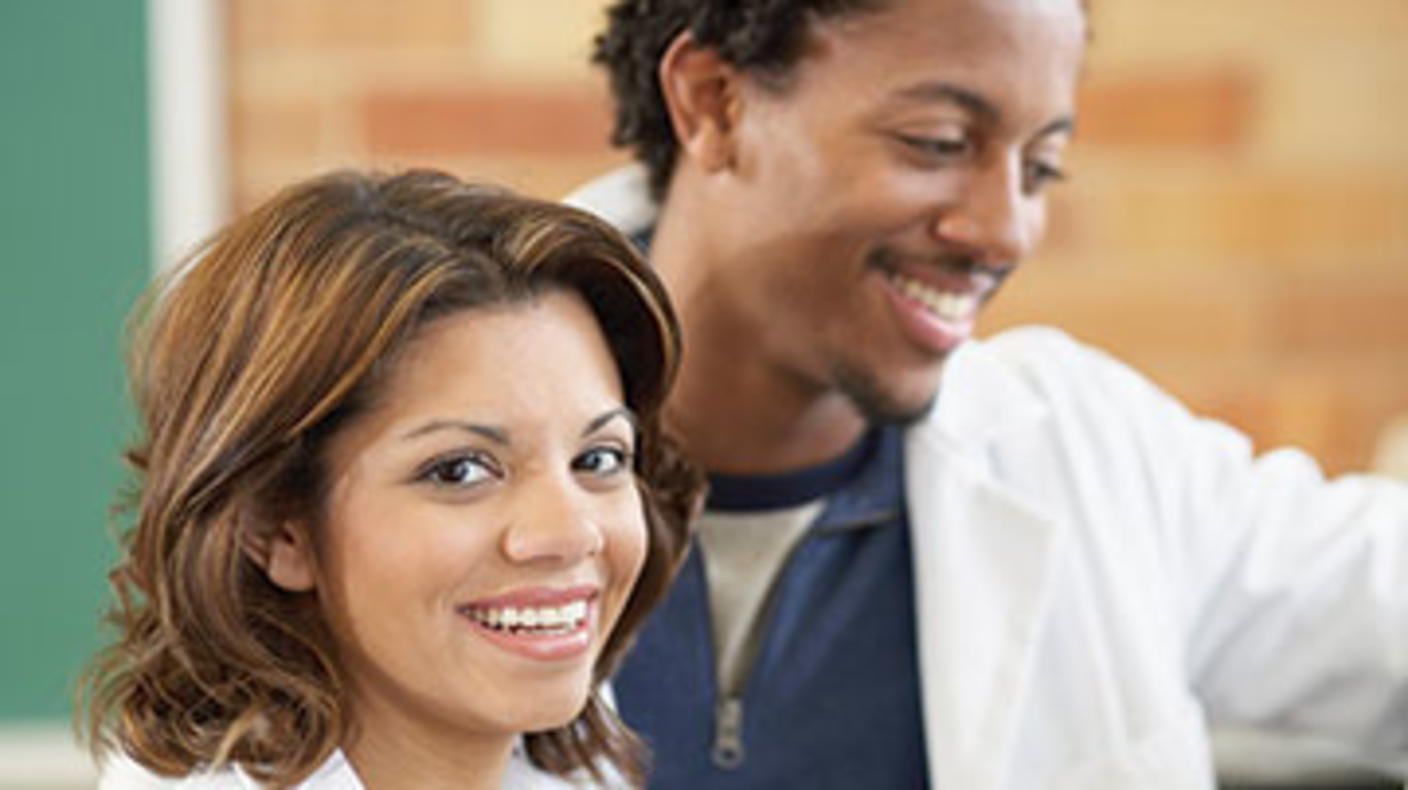 A smiling man and woman wearing white lab coats.