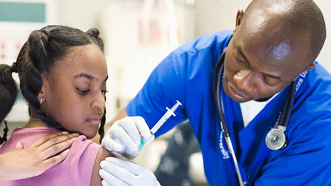 Doctor giving a girl a shot in the upper arm