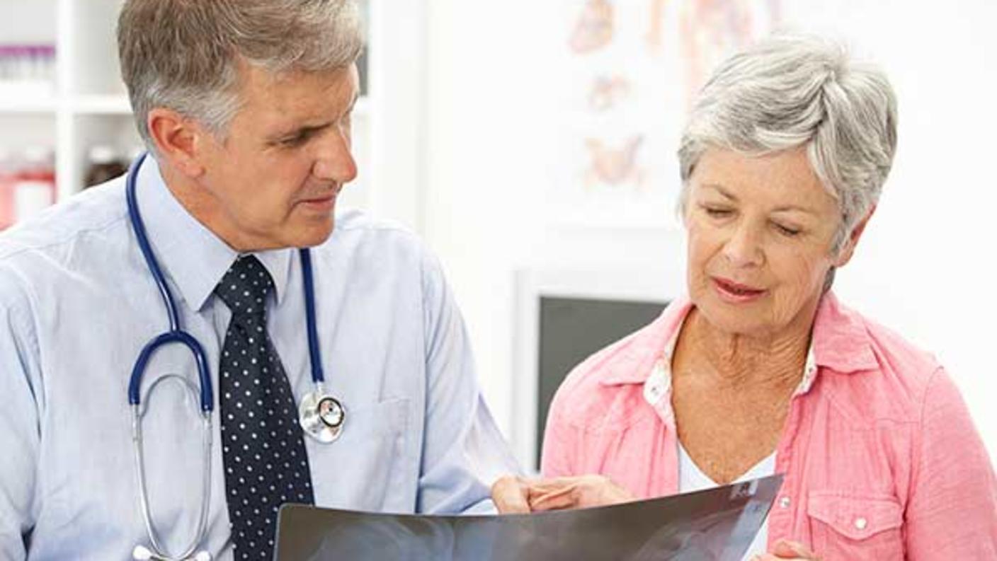Male doctor and female patient look at a digital image the doctor holds.