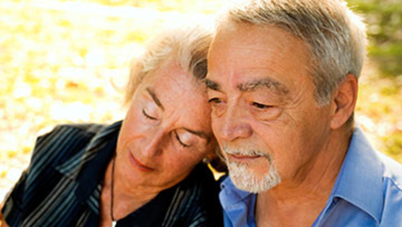 A couple sitting outside as the woman leans her head on the man's shoulder