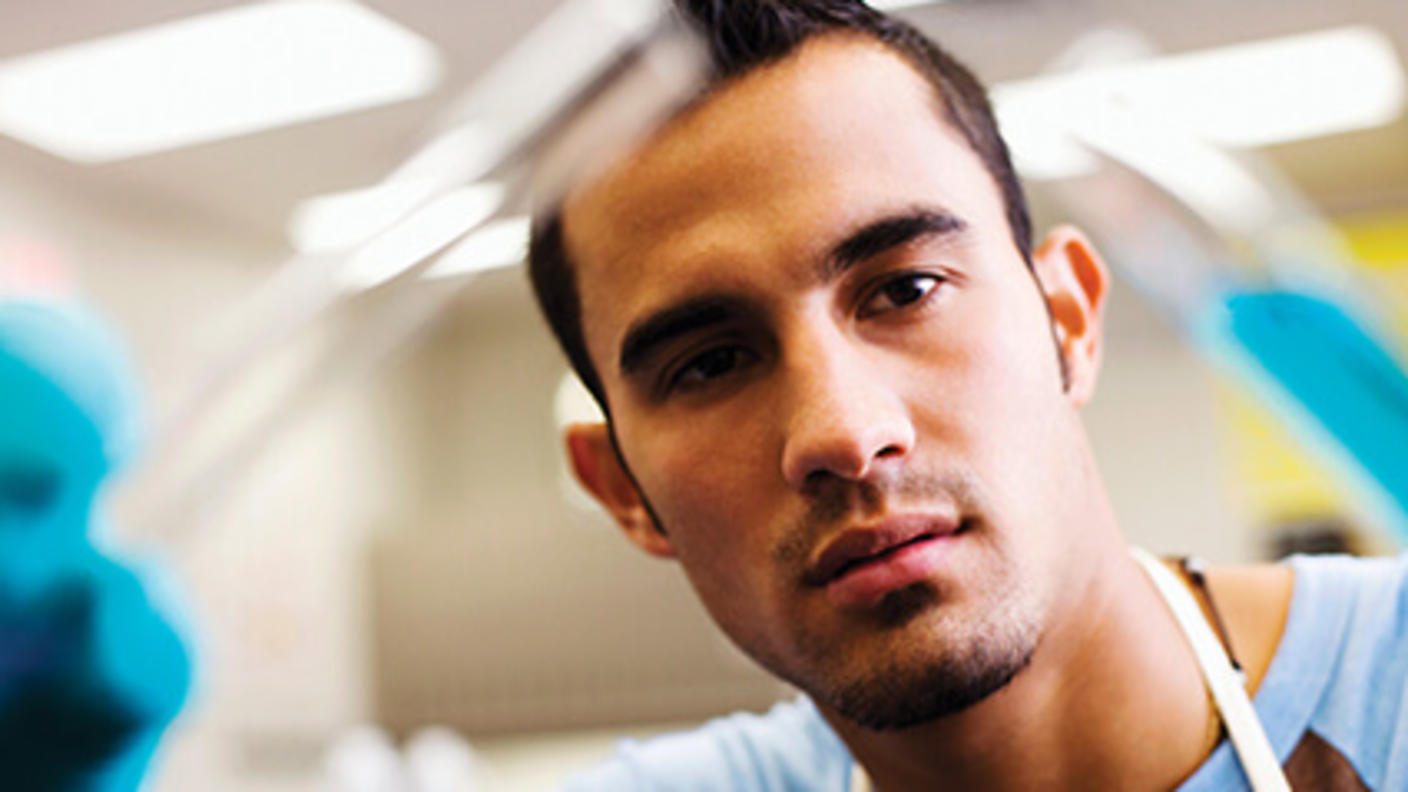 Male technician examining a vial.