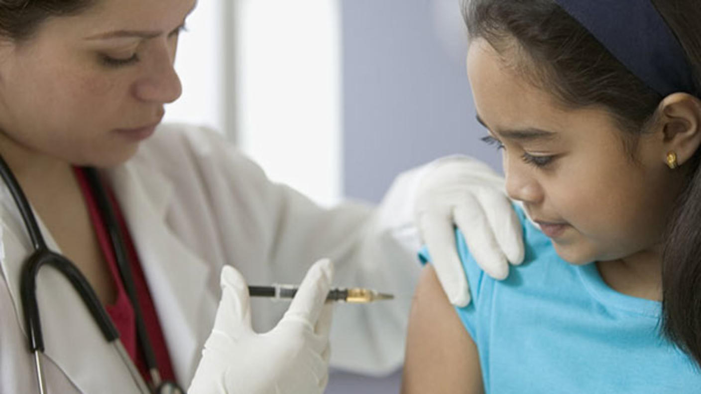 Doctor administering vaccination to young girl