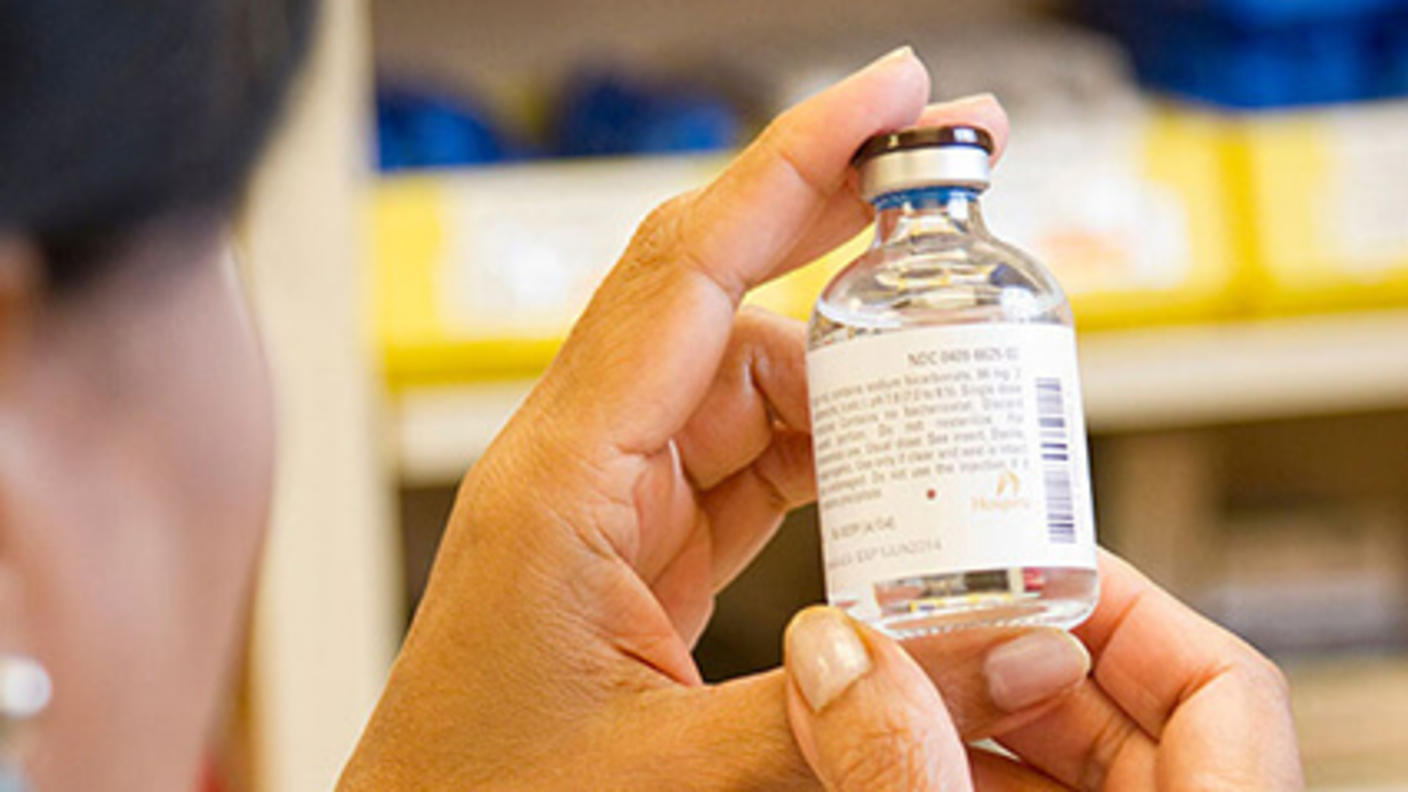 Pharmacist examining a drug vial.