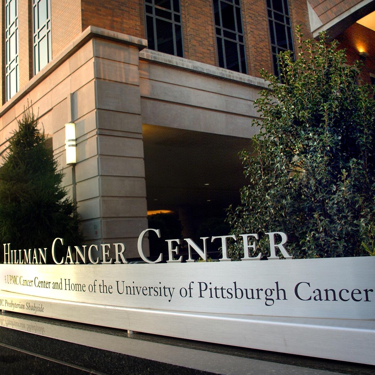 Exterior photo of the University of Pittsburgh Cancer Institute. The sign of the institute is in the foreground with part of the building in the background. 