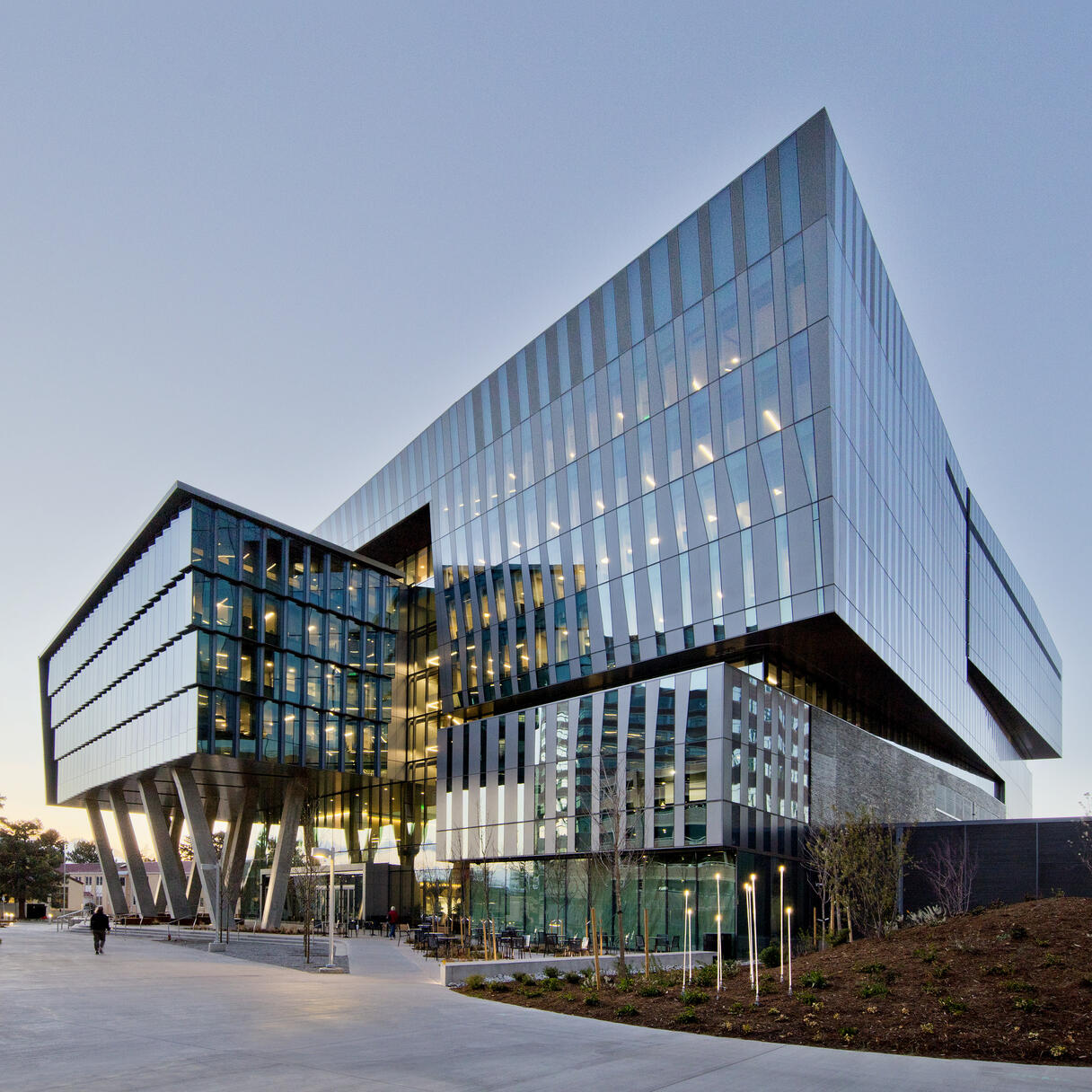 University of Colorado Cancer Center, a modern glass building with angular cantilevered sections and lit interiors at dusk.