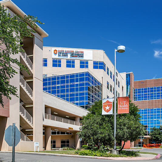 Mays Cancer Center at UT Health San Antonio, a multi-building complex with glass windows, signage, and street-level view.