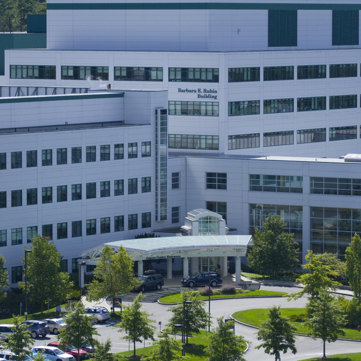 Norris Cotton Cancer Center at Dartmouth-Hitchcock Medical Center, a large white building with rows of windows, a covered entrance, and surrounding trees.