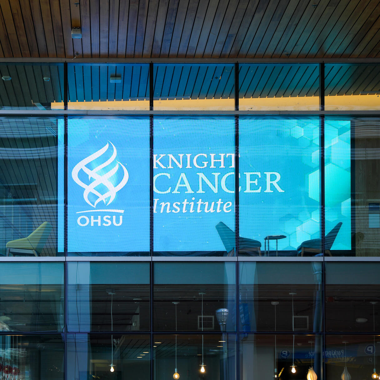 OHSU Knight Cancer Institute logo displayed on a large glass window, with interior seating visible behind it.