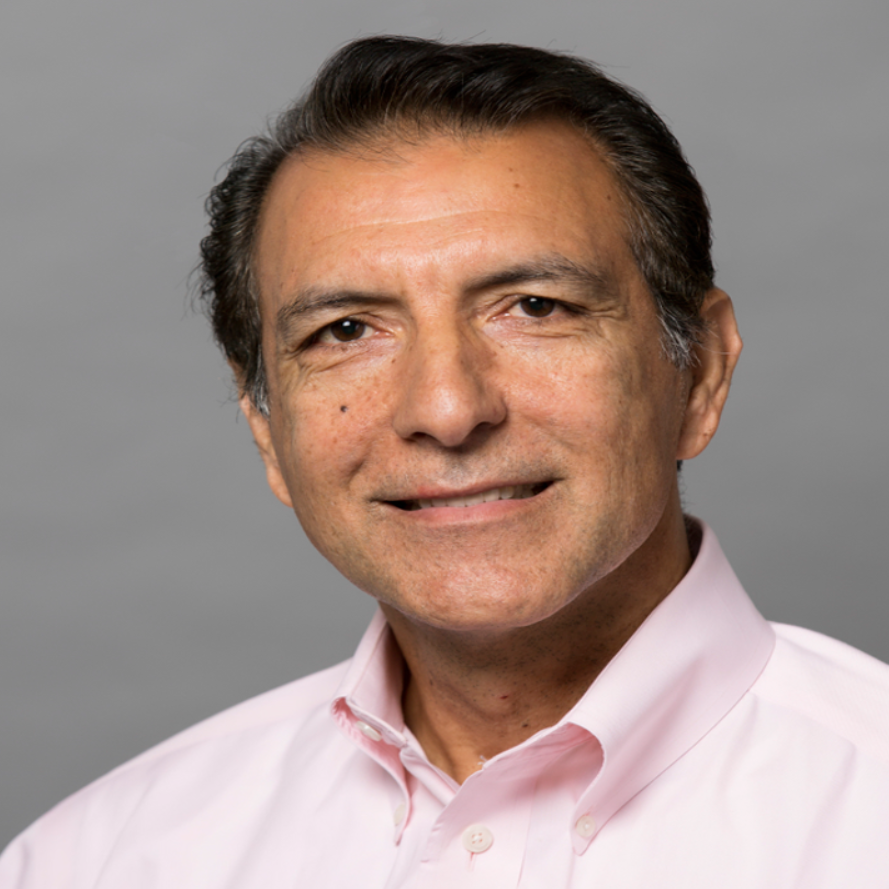 Professional headshot of Dr. Daoud Meerzaman. He's smiling at the camera dress in a pink button-down shirt against a gray backdrop.