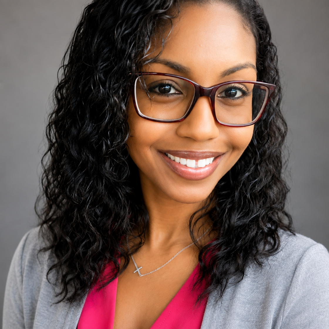 Photo of Samantha Caesar-Johnson wearing a red shirt, grey sweater, and black glasses