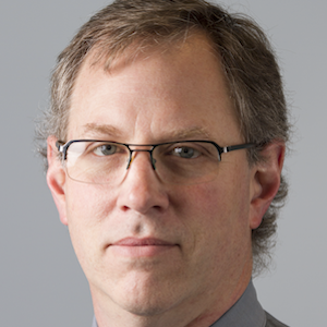 Headshot of Dr. Martin Ferguson, a man wearing glasses, a grey collared shirt, and a brown tie
