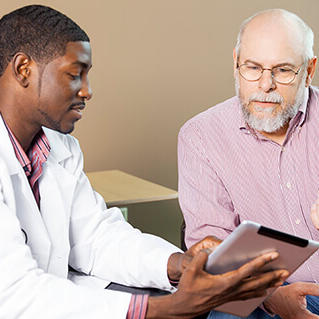 Young African-American doctor showing older male patient something on an iPad