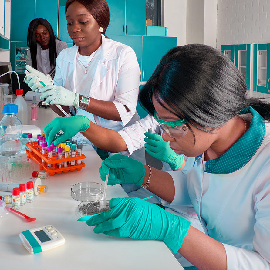Three female African scientists working in research laboratory, testing various substances